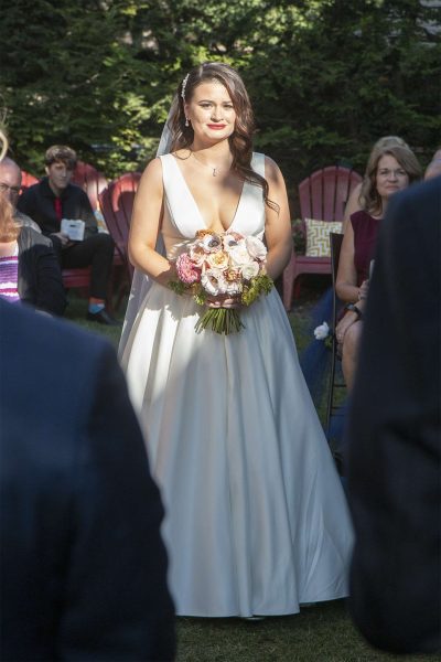 Beautiful bride with bouquet walks down garden aisle at her Cream City Garden wedding ceremony in Milwaukee, WI.