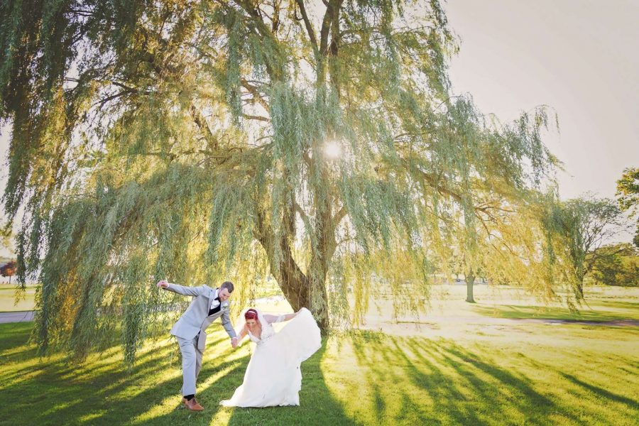 Bride and groom bow underneath a sunlit willow tree-Allysha Noelle Photography