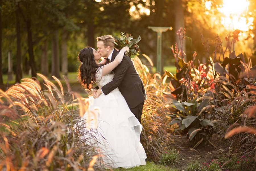Bride and groom embrace in lush garden area at sunset-Allysha Noelle Photography
