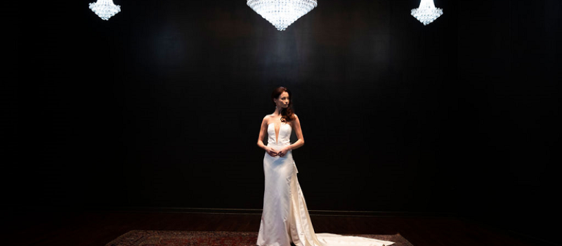 Bride center stage alone at The Fitzgerald with dark background and chandeliers above.