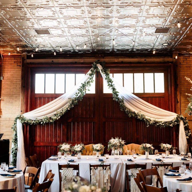 dinner space showing metal imprinted ceiling tiles and gold mustard velvet chairs for bride and groom