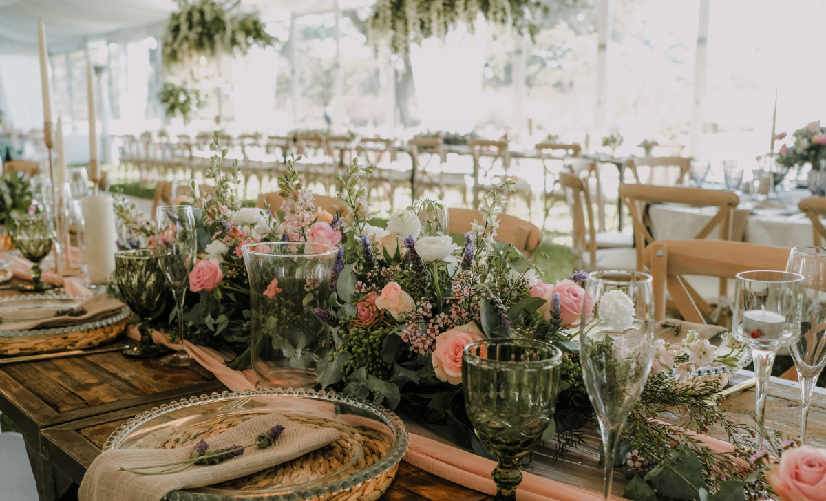 Wedding Table inspiration with large floral arrangement in pinks and greens. Chargers and clear dinner plates with green glassware.