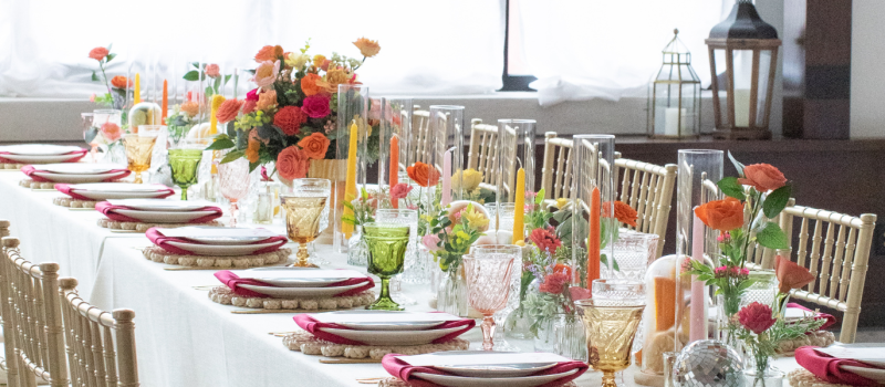 Wedding table decor with hues or bright colors and gold chiavari chairs.