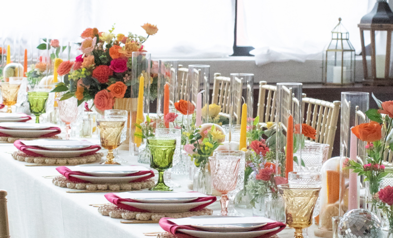 Wedding table decor with hues or bright colors and gold chiavari chairs.
