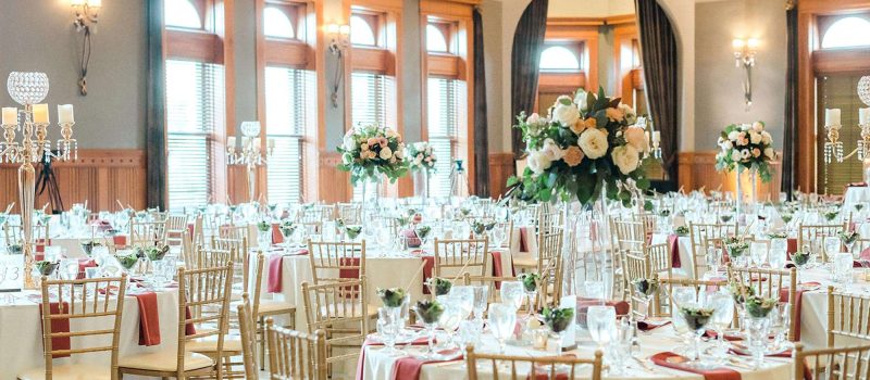 Reception tables decorated with beige/burnt orange linens, floral hurricanes and gold and jeweled centerpieces